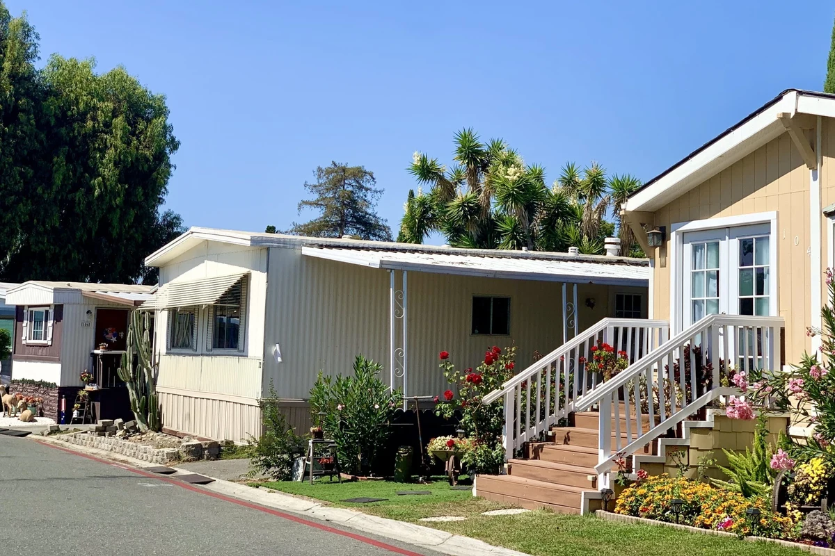 Mobile home park community with neatly arranged homes, paved roads, and evening lighting